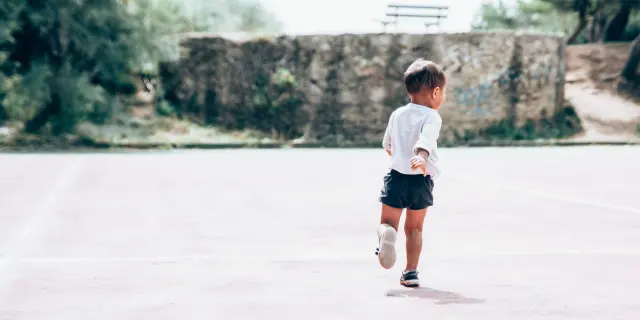 Un bambino corre in un campo da gioco.